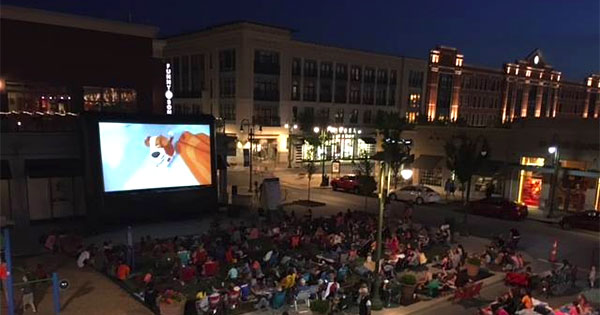 outdoor movie on LED display with crowd in front